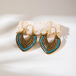 Detail showing vintage hollow heart earrings with blue beads and intricate metal engraving