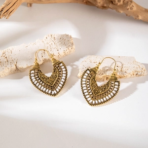 Detail of vintage bohemian hollow heart earrings with white woven trim on stone