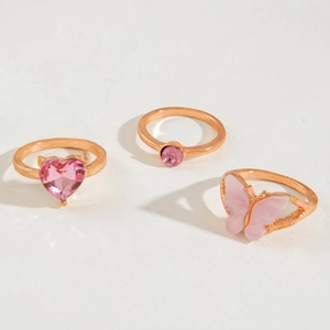 Detail of three rose gold rings featuring pink heart-shaped crystal and butterfly design