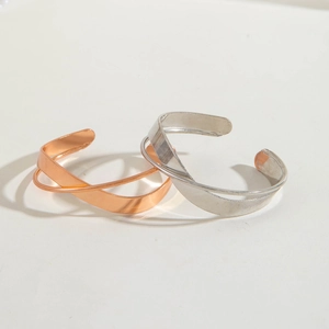 Close-up of rose gold and silver interlocking crossover metal bangles with polished finish