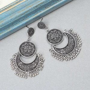 Detail of vintage silver boho earrings featuring floral engravings and hanging metal beads