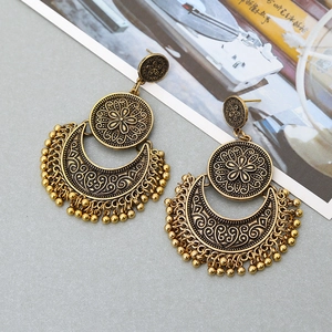 Detail of vintage bohemian hollow flower earrings with antique gold finish and bead tassels