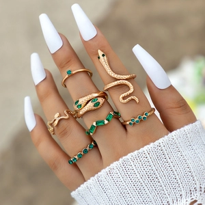 7-piece gold ring set featuring snake designs and green gemstones on a model hand