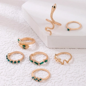 Detailed view of 7-piece gold ring set featuring green gemstones and snake-shaped textures