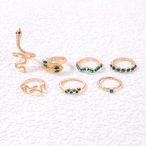 Close-up of a 7-piece vintage gold ring set with green gemstones and snake motifs