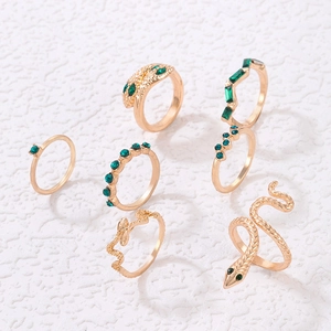 Flat lay of a 7-piece vintage gold-tone ring set featuring snake designs and green gemstones