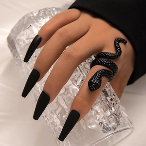 Close-up of black snake ring with scale texture worn by a model holding a glass