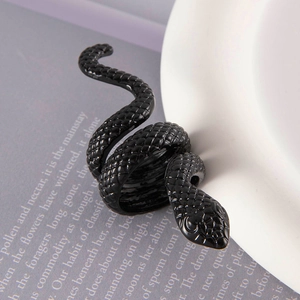 Detailed view of punk black snake ring with scale texture on white ceramic and magazine