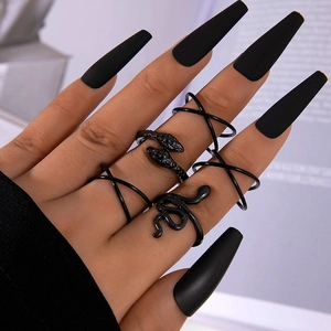 Detail of five black punk style snake rings on hand with matte finish and dark aesthetic