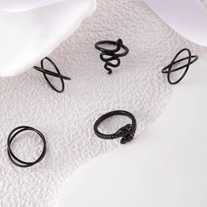 Detailed view of 5-piece black snake and geometric punk ring set on textured background