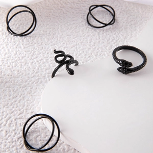 Macro view of matte black snake ring and minimalist layered ring set on white background