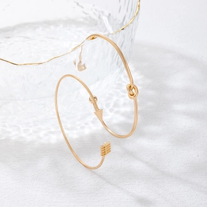 Détail d'un bracelet flèche doré avec un nœud décoratif sur verre texturé
