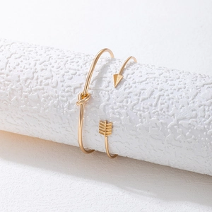 Ensemble de bracelets dorés minimalistes avec motifs flèche et nœud sur socle texturé