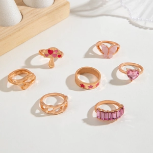 Detail view of 7-piece rose gold ring set featuring pink hearts and butterfly motifs