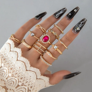 Detalle de set de 14 anillos bohemios dorados con piedras rosas y motivos de estrella