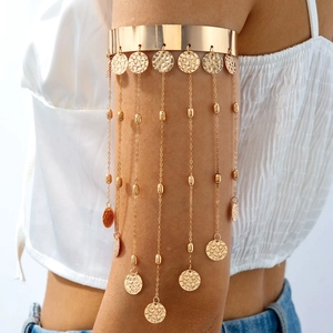 Détail d'un bracelet de bras doré avec franges métalliques et pièces de monnaie boho