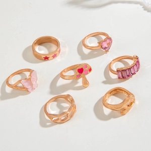 Set de 7 anillos dorados con motivos de setas rosas, estrellas, corazones y mariposas