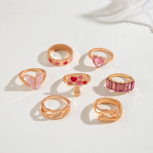Set de 7 anillos dorados con diseños de hongos estrellas y mariposas en esmalte rosa