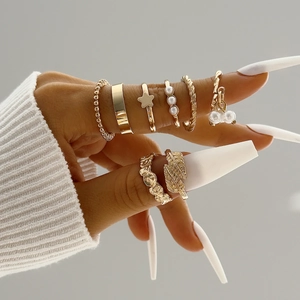 Close-up of 8-piece gold butterfly and pearl rings set on fingers with long nails