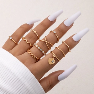 Nine-piece gold ring set featuring heart charms, stars, and crystals on a model hand