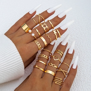 Detailed close-up of gold butterfly and heart ring set worn on fingers with pearl accents