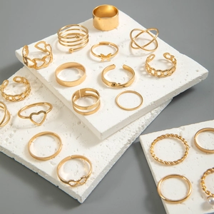 Close-up of gold butterfly and heart alloy rings on a white stone textured surface