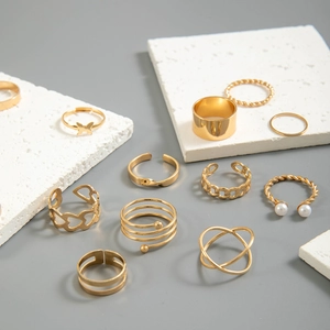 Detail of gold-plated butterfly and heart ring set displayed on textured white stone