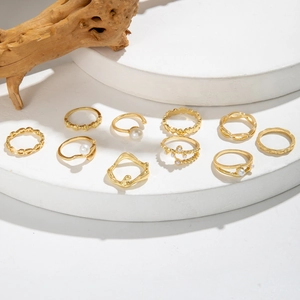 Dettaglio del set di 10 anelli dorati geometrici con perle su espositore in pietra