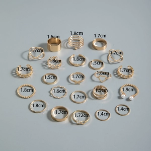 Flat lay of 21-piece gold ring set with butterfly and heart motifs on gray backdrop