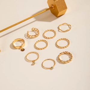 Flat lay of a 9-piece gold alloy ring set with twist texture and rhinestone details