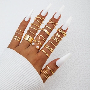 Close-up of bohemian gold butterfly ring set with heart and pearl details on model