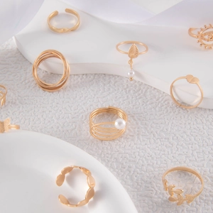 Detail view of gold butterfly and evil eye ring set with pearls on white texture