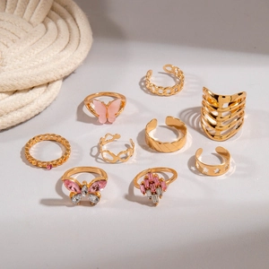 Macro shot of 9-piece gold ring set featuring pink butterflies and star engravings