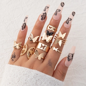 Dettaglio di anelli a farfalla bohémien in oro su mano con nail art a tema farfalla