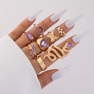 Detail of 9pcs gold ring set with purple gems, butterfly and snake motifs on hand