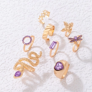 Detail of 9-piece gold ring set featuring purple stones, butterfly, and snake charms
