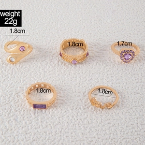 Detailed view of 5-piece gold alloy ring set with purple gems and size measurements