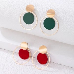 Detalle de pendientes redondos geométricos de metal en verde oscuro y rojo dorado
