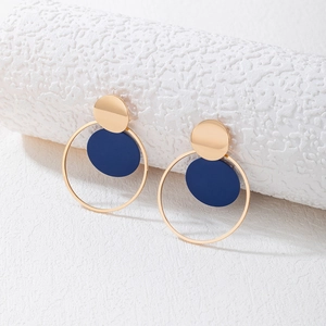 Detalle de pendientes geométricos de metal dorado y azul marino con acabado pulido