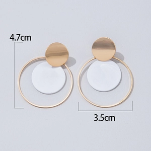 Detalle de pendientes geométricos dorados con colgante blanco y medida de altura de 4,7 cm