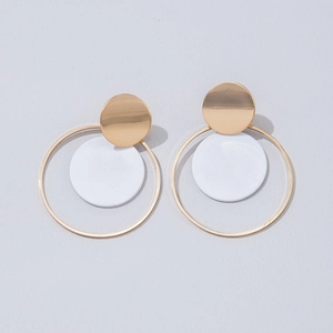 Detalle de pendientes geométricos dorados con dijes blancos para mujer