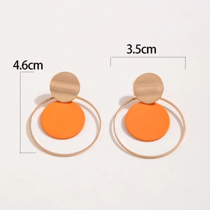 Detalle de los pendientes geométricos de metal con discos naranjas y medida de 4,6 cm