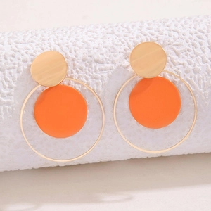 Detalle de pendientes geométricos dorados y naranjas con aros metálicos minimalistas