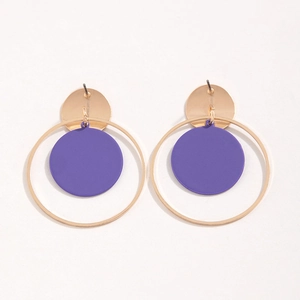 Detalle de pendientes geométricos dorados con anillos y discos morados mate