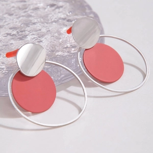 Detalle de pendientes circulares plata y rojo coral sobre cristal decorativo morado