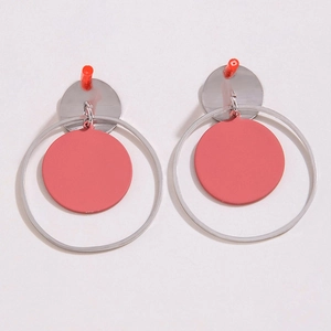 Detalle de pendientes geométricos plateados con discos rosas mate sobre rosa
