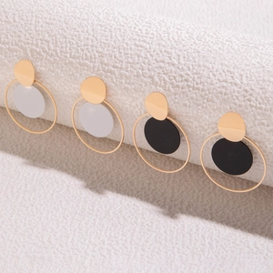 Detalle de pendientes circulares geométricos en blanco y negro sobre un soporte blanco