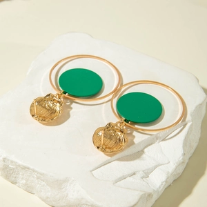 Detalle de pendientes de aro geométricos dorados y verde esmeralda sobre mármol blanco