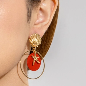 Detalle de los pendientes de disco rojo y estrella de mar dorada en la oreja