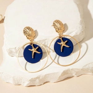 Detalle de pendientes marinos con conchas doradas, discos azules y estrellas de mar
